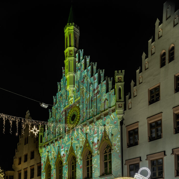 Beleuchtete Fassade und XXL-Christbaumkugel vor dem Rathaus abends